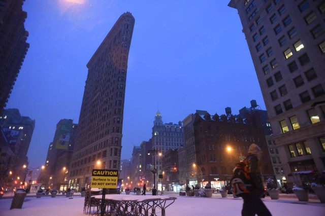 A man walks the streets near Madison Square Park at the foot of the Flatiron building in Manhattan during a snowstorm in New York on March 14, 2017. Winter Storm Stella dumped snow and sleet Tuesday across the northeastern United States where thousands of flights were canceled and schools closed, but appeared less severe than initially forecast. After daybreak the National Weather Service (NWS) revised down its predicted snow accumulation for the city of New York, saying that the storm had moved across the coast. / AFP PHOTO / SAUL LOEB