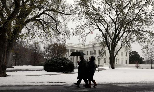 A man holds an umbrella as he walks from the White House on a snowy morning in Washington, U.S., March 14, 2017. REUTERS/Kevin Lamarque