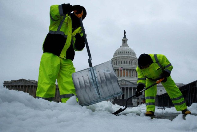 Workers clear frozen precipitation from a walkway at the U.S. Capitol in Washington, U.S., March 14, 2017. REUTERS/Jonathan Ernst