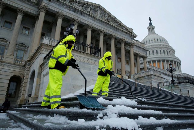 Workers clear frozen precipitation from the steps of the U.S. Capitol, in Washington, U.S., March 14, 2017. REUTERS/Jonathan Ernst