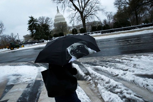 A woman walks to work as a bit of frozen rain continues to fall on Capitol Hill, in Washington, U.S., March 14, 2017. REUTERS/Jonathan Ernst