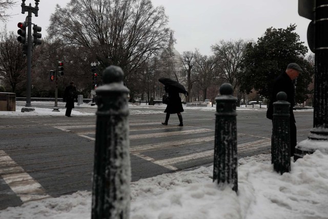 Commuters walk through the snow outside the Capitol Building in Washington, D.C., U.S. March 14, 2017. REUTERS/Aaron P. Bernstein