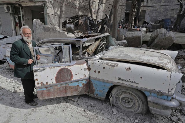 A picture taken on March 9, 2017, shows 70-year-old Mohammed Mohiedin Anis, or Abu Omar, inspecting his 1957 Mercury Montclair outside his home in Aleppo's formerly rebel-held al-Shaar neighbourhood.  / AFP PHOTO / JOSEPH EID