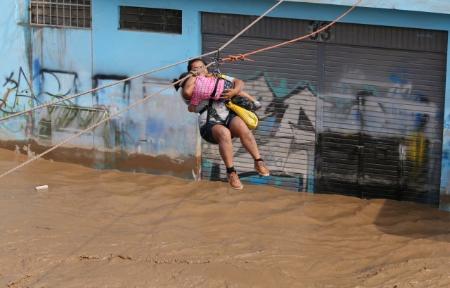REFILE - CORRECTING NAME OF THE RIVER A woman and a child are evacuated with a zip line after the Huaycoloro river overflooded its banks sending torrents of mud and water rushing through the streets in Huachipa, Peru, March 17, 2017. REUTERS/Guadalupe Pardo
