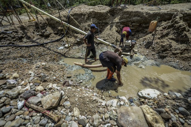 Men work at Nacupay gold mine on the bank of a river in El Callao, Bolivar state, southeastern Venezuela on February 24, 2017. Although life in the mines of eastern Venezuela is hard and dangerous, tens of thousands from all over the country head for the mines daily in overcrowded trucks, pushed by the rise in gold prices and by the severe economic crisis affecting the country, aggravated recently by the drop in oil prices. / AFP PHOTO / JUAN BARRETO