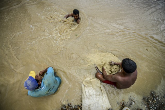 Men work at Nacupay gold mine on the bank of a river in El Callao, Bolivar state, southeastern Venezuela on February 24, 2017. Although life in the mines of eastern Venezuela is hard and dangerous, tens of thousands from all over the country head for the mines daily in overcrowded trucks, pushed by the rise in gold prices and by the severe economic crisis affecting the country, aggravated recently by the drop in oil prices. / AFP PHOTO / JUAN BARRETO