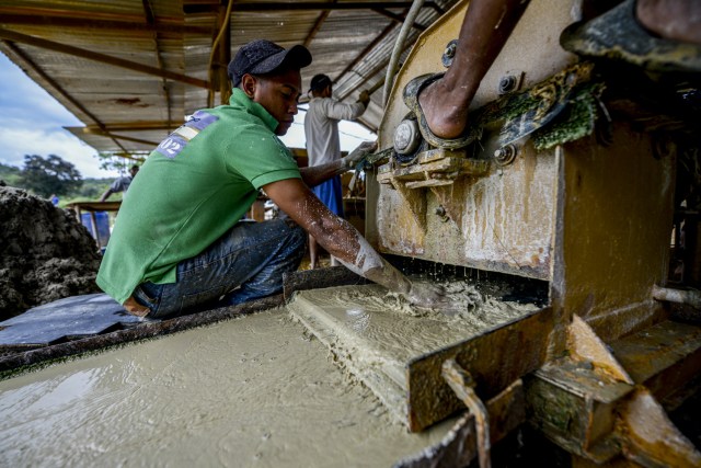 Jorge Sanchez, 24, works with the mixture in a stone crusher machine in a gold mine in El Callao, Bolivar state, southeastern Venezuela on February 25, 2017. Although life in the mines of eastern Venezuela is hard and dangerous, tens of thousands from all over the country head for the mines daily in overcrowded trucks, pushed by the rise in gold prices and by the severe economic crisis affecting the country, aggravated recently by the drop in oil prices. / AFP PHOTO / JUAN BARRETO