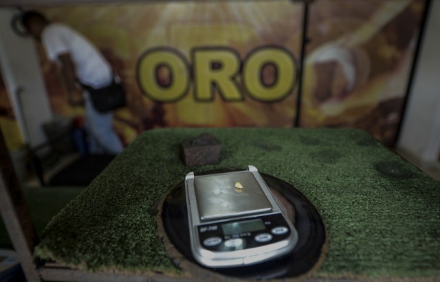 A gold stone is weighed at a specialized store in El Callao, Bolivar state, southeastern Venezuela on February 25, 2017. Although life in the mines of eastern Venezuela is hard and dangerous, tens of thousands from all over the country head for the mines daily in overcrowded trucks, pushed by the rise in gold prices and by the severe economic crisis affecting the country, aggravated recently by the drop in oil prices. / AFP PHOTO / JUAN BARRETO / TO GO WITH AFP STORY by Maria Isabel SANCHEZ