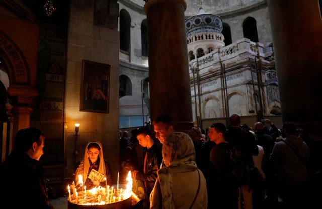 Worshippers light candles as the newly restored Edicule, the ancient structure housing the tomb, which according to Christian belief is where Jesus's body was anointed and buried, is seen in the background at the Church of the Holy Sepulchre in Jerusalem's Old City March 20, 2017. REUTERS/Ronen Zvulun