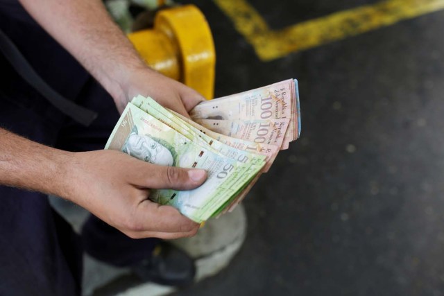 A worker counts Venezuelan bolivar notes at a gas station of Venezuelan state oil company PDVSA in Caracas, Venezuela March 21, 2017. REUTERS/Marco Bello