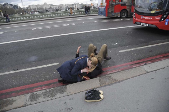 A woman assist an injured person after an incident on Westminster Bridge in London, March 22, 2017. REUTERS/Toby Melville