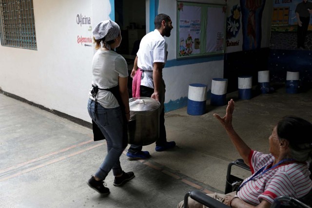 A woman greets chefs of La Casa Bistro restaurant, members of the "Full Stomach, Happy Heart" (Barriga llena, corazon contento) charity, as they arrive carrying a cooking pot full of soup donated to the Mother Teresa of Calcutta nursing home, in Caracas, Venezuela February 20, 2017. Picture taken February 20, 2017. REUTERS/Marco Bello