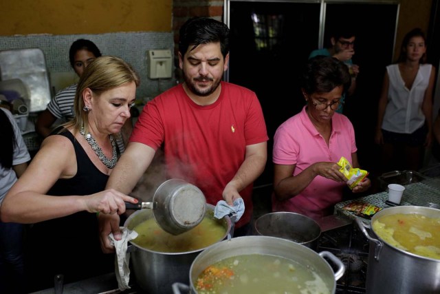 Diego Prada (C), Maria Luisa Pombo (L) and other volunteers of the Make The Difference (Haz La Diferencia) charity initiative prepare soup to be donated, at Maria Luisa's kitchen in Caracas, Venezuela March12, 2017. Picture taken March 12, 2017. REUTERS/Marco Bello
