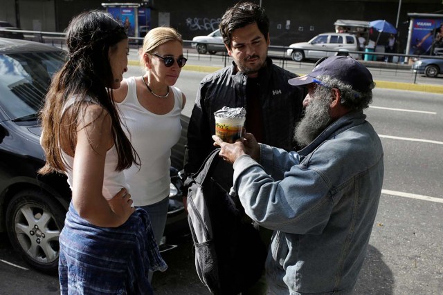 Diego Prada (2nd R) and Maria Luisa Pombo (2nd L), Volunteers of the Make The Difference (Haz La Diferencia) charity initiative, speak with a homeless man after giving him a cup of soup and an arepa in Caracas, Venezuela March 5, 2017. Picture taken March 5, 2017. REUTERS/Marco Bello