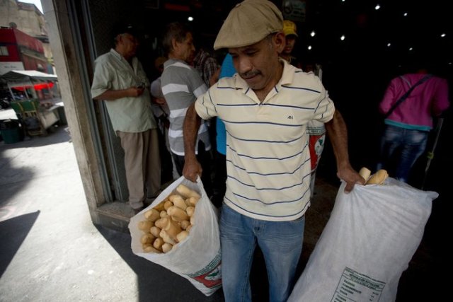 Un empleado de la panadería Minka, intervenida por el Estado, lleva bolsas de pan para ser distribuidas a tiendas estatales en Caracas. Credit Fernando Llano/Associated Press