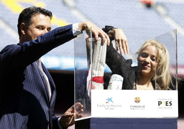 La Caixa Foundation's director of social and educational endeavours Xavier Bertolin (L) and Colombian singer and founder of Colombian NGO, Fundacion Pies Descalzos, Shakira Mebarak, introduce newspapers into a memory box at the Camp Nou stadium in Barcelona on March 28, 2017 during the presentation of the project to build a new school in the restive region of Barranquilla (Colombia), in collaboration with the foundations of FC Barcelona and La Caixa. / AFP PHOTO / Pau Barrena