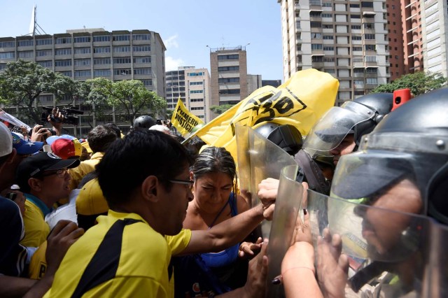 Venezuelan opposition activists clash with riot police during a demonstration in Caracas on April 4, 2017. Venezuela has been mired in turmoil since the Supreme Court last week tried to tighten Maduro's grip on power by assuming legislative powers from the National Assembly -- a move opponents had angrily branded as a "coup d'etat." / AFP PHOTO / JUAN BARRETO