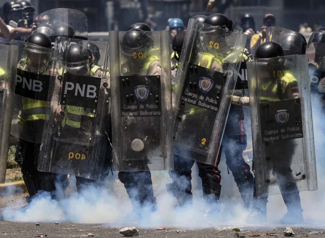 Bolivarian police agents hold their shields and prepare for confrontation during a protest against Nicolas Maduro's government in Caracas on April 4, 2017. Protesters clashed with police in Venezuela Tuesday as the opposition mobilized against moves to tighten President Nicolas Maduro's grip on power. Protesters hurled stones at riot police who fired tear gas as they blocked the demonstrators from advancing through central Caracas, where pro-government activists were also planning to march. / AFP PHOTO / JUAN BARRETO