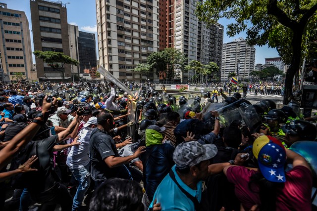 Venezuela's opposition activists clash with riot police agents during a protest against Nicolas Maduro's government in Caracas on April 4, 2017. Protesters clashed with police in Venezuela Tuesday as the opposition mobilized against moves to tighten President Nicolas Maduro's grip on power. Protesters hurled stones at riot police who fired tear gas as they blocked the demonstrators from advancing through central Caracas, where pro-government activists were also planning to march.  / AFP PHOTO / JUAN BARRETO