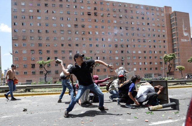 Venezuela's opposition activists clash with riot police agents during a protest against Nicolas Maduro's government in Caracas on April 4, 2017. Protesters clashed with police in Venezuela Tuesday as the opposition mobilized against moves to tighten President Nicolas Maduro's grip on power. Protesters hurled stones at riot police who fired tear gas as they blocked the demonstrators from advancing through central Caracas, where pro-government activists were also planning to march.  / AFP PHOTO / JUAN BARRETO