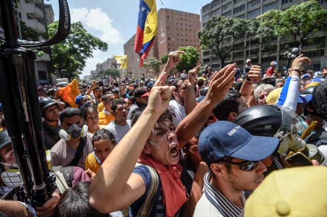 Venezuela's opposition activists clash with riot police agents during a protest against Nicolas Maduro's government in Caracas on April 4, 2017. Protesters clashed with police in Venezuela Tuesday as the opposition mobilized against moves to tighten President Nicolas Maduro's grip on power. Protesters hurled stones at riot police who fired tear gas as they blocked the demonstrators from advancing through central Caracas, where pro-government activists were also planning to march. / AFP PHOTO / JUAN BARRETO