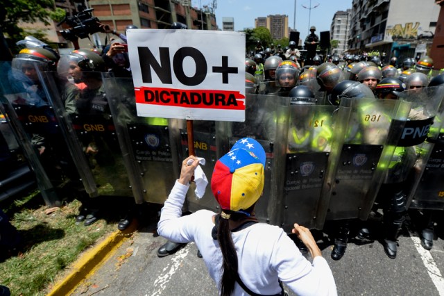 Opposition activists protest against President Nicolas Maduro's government in Caracas on April 4, 2017.  Activists clashed with police in Venezuela Tuesday as the opposition mobilized against moves to tighten President Nicolas Maduro's grip on power. Protesters hurled stones at riot police who fired tear gas as they blocked the demonstrators from advancing through central Caracas, where pro-government activists were also planning to march. / AFP PHOTO / FEDERICO PARRA