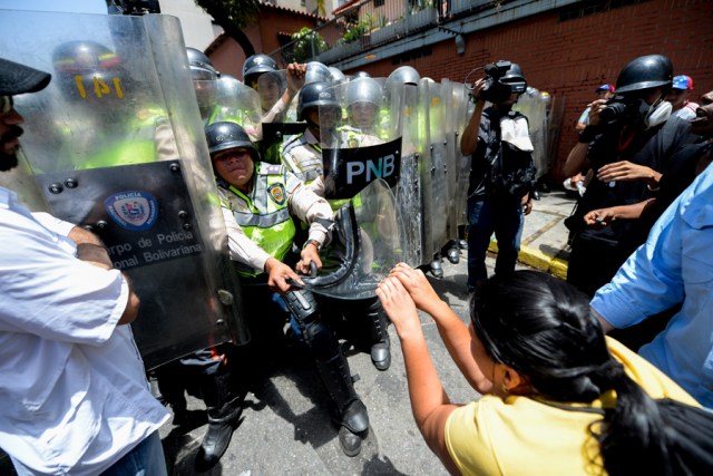Demosntrators scuffle with riot police during a protest against President Nicolas Maduro's government in Caracas on April 4, 2017.  Activists clashed with police in Venezuela Tuesday as the opposition mobilized against moves to tighten President Nicolas Maduro's grip on power. Protesters hurled stones at riot police who fired tear gas as they blocked the demonstrators from advancing through central Caracas, where pro-government activists were also planning to march. / AFP PHOTO / FEDERICO PARRA