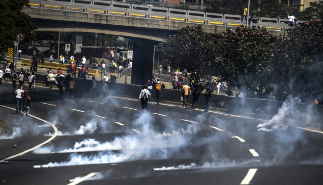 Riot police fire tear gas grenades at demonstrators during a protest against President Nicolas Maduro's government in Caracas on April 4, 2017.  Activists clashed with police in Venezuela Tuesday as the opposition mobilized against moves to tighten President Nicolas Maduro's grip on power. Protesters hurled stones at riot police who fired tear gas as they blocked the demonstrators from advancing through central Caracas, where pro-government activists were also planning to march. / AFP PHOTO / JUAN BARRETO