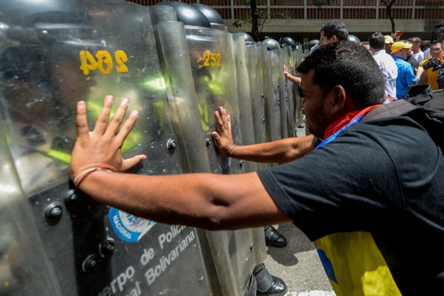 Demonstrators scuffle with riot police during a protest against President Nicolas Maduro's government in Caracas on April 4, 2017.  Activists clashed with police in Venezuela Tuesday as the opposition mobilized against moves to tighten President Nicolas Maduro's grip on power. Protesters hurled stones at riot police who fired tear gas as they blocked the demonstrators from advancing through central Caracas, where pro-government activists were also planning to march. / AFP PHOTO / FEDERICO PARRA