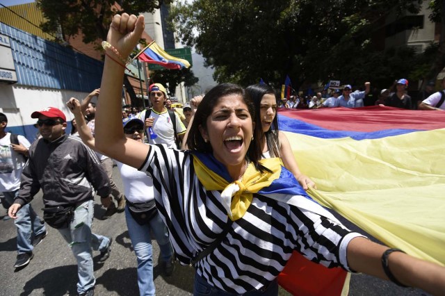 Venezuelan opposition activists shout slogans during a protest against the government of President Nicolas Maduro on April 6, 2017 in Caracas. The center-right opposition vowed fresh street protests -after earlier unrest left dozens of people injured - to increase pressure on Maduro, whom they blame for the country's economic crisis. / AFP PHOTO / JUAN BARRETO