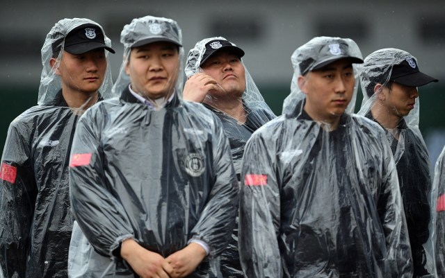 Security stands wearing rain gear in the paddock after the second practice session of the Formula One Chinese Grand Prix in Shanghai on April 7, 2017. / AFP PHOTO / Johannes EISELE