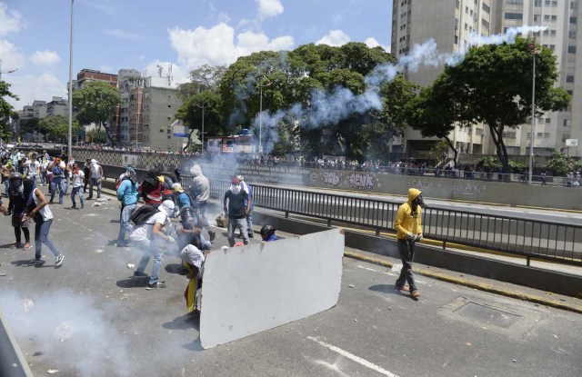 Demonstrators against Nicolas Maduro's government clash with riot police eastern Caracas on April 8, 2017. The opposition is accusing pro-Maduro Supreme Court judges of attempting an internal "coup d'etat" for attempting to take over the opposition-majority legislature's powers last week. The socialist president's supporters held counter-demonstrations on Thursday, condemning Maduro's opponents as "imperialists" plotting with the United States to oust him. / AFP PHOTO / FEDERICO PARRA