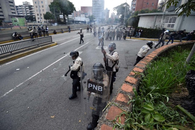 Riot police deploy during demonstrations against Nicolas Maduro's government at easter Caracas on April 8, 2017. The opposition is accusing pro-Maduro Supreme Court judges of attempting an internal "coup d'etat" for attempting to take over the opposition-majority legislature's powers last week. The socialist president's supporters held counter-demonstrations on Thursday, condemning Maduro's opponents as "imperialists" plotting with the United States to oust him. / AFP PHOTO / JUAN BARRETO