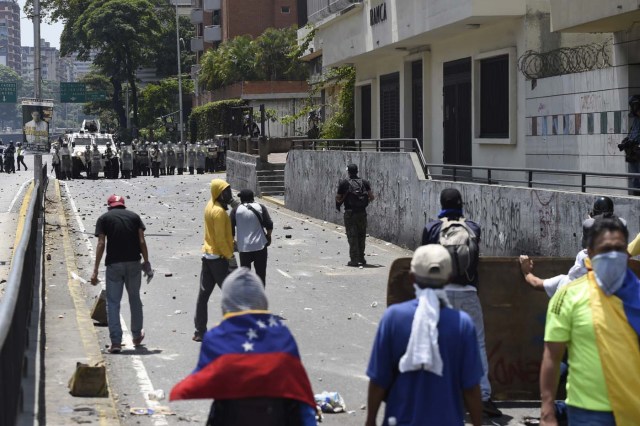 Demonstrators against Nicolas Maduro's government clash with riot police in Caracas on April 8, 2017. The opposition is accusing pro-Maduro Supreme Court judges of attempting an internal "coup d'etat" for attempting to take over the opposition-majority legislature's powers last week. The socialist president's supporters held counter-demonstrations on Thursday, condemning Maduro's opponents as "imperialists" plotting with the United States to oust him. / AFP PHOTO / JUAN BARRETO