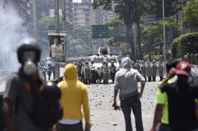 Demonstrators against Nicolas Maduro's government clash with riot police at eastern Caracas on April 8, 2017. The opposition is accusing pro-Maduro Supreme Court judges of attempting an internal "coup d'etat" for attempting to take over the opposition-majority legislature's powers last week. The socialist president's supporters held counter-demonstrations on Thursday, condemning Maduro's opponents as "imperialists" plotting with the United States to oust him. / AFP PHOTO / JUAN BARRETO