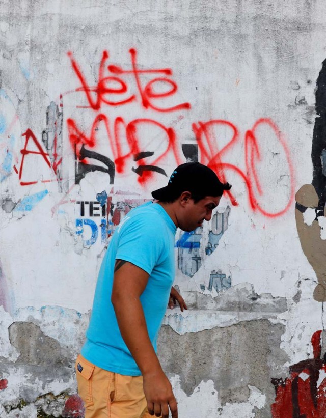A pedestrian walks past a graffiti that reads "Maduro go out" during a rally in Caracas, Venezuela, April 8, 2017. REUTERS/Carlos Garcia Rawlins