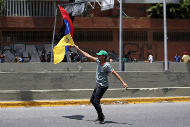 A demonstrator holds a Venezuelan flag during clashes with riot police during a rally in Caracas, Venezuela, April 8, 2017. REUTERS/Carlos Garcia Rawlins