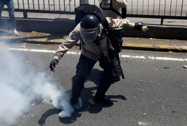 REFILE - CLARIFYING CAPTIONA riot police officer attempts to kick a tear gas canister during clashes with opposition supporters in Caracas, Venezuela, April 8, 2017. REUTERS/Carlos Garcia Rawlins