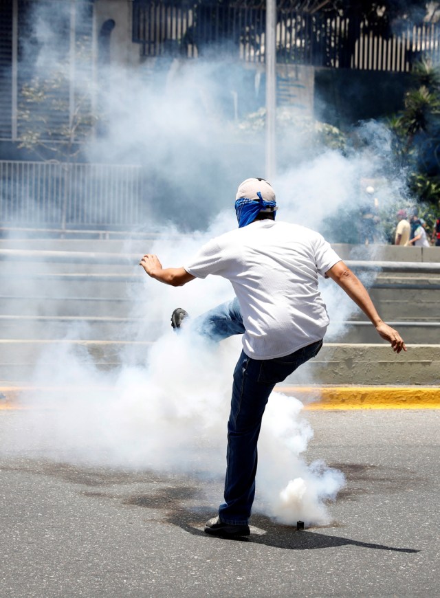 REFILE - CLARFYING CAPTION A demonstrator kicks a tear gas canister during an opposition rally in Caracas, Venezuela, April 8, 2017. REUTERS/Carlos Garcia Rawlins