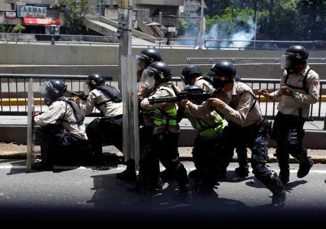 Riot police officers take cover during clashes with demonstrators at a rally in Caracas, Venezuela, April 8, 2017. REUTERS/Carlos Garcia Rawlins