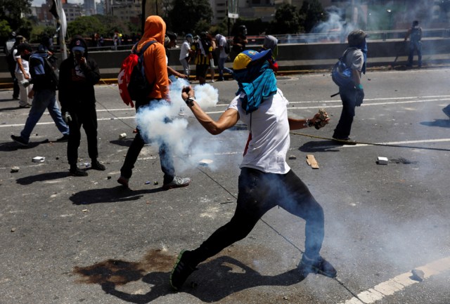 A demonstrator throws back a tear gas canister while clashing with riot police during a rally in Caracas, Venezuela, April 8, 2017. REUTERS/Carlos Garcia Rawlins