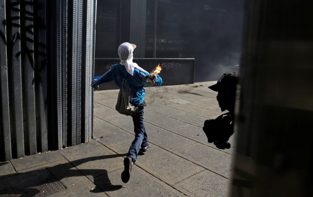 A demonstrator throws a petrol bomb towards an office of the Supreme Court of Justice during a rally in Caracas, Venezuela, April 8, 2017. REUTERS/Marco Bello TPX IMAGES OF THE DAY