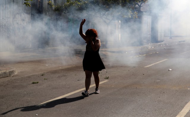 A woman walks away from tear gas during a rally in Caracas, Venezuela, April 8, 2017. REUTERS/Marco Bello