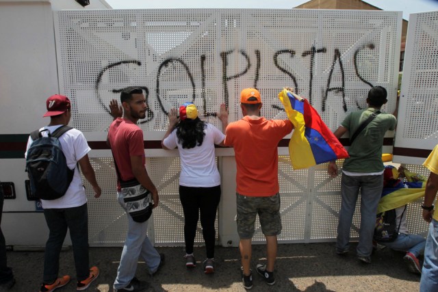 Opposition supporters gather near an anti-riot barricade with a graffiti that reads "coup" during a rally against Venezuela's President Nicolas Maduro's government in Maracaibo, Venezuela April 8, 2017. REUTERS/Isaac Urrutia FOR EDITORIAL USE ONLY. NO RESALES. NO ARCHIVES.