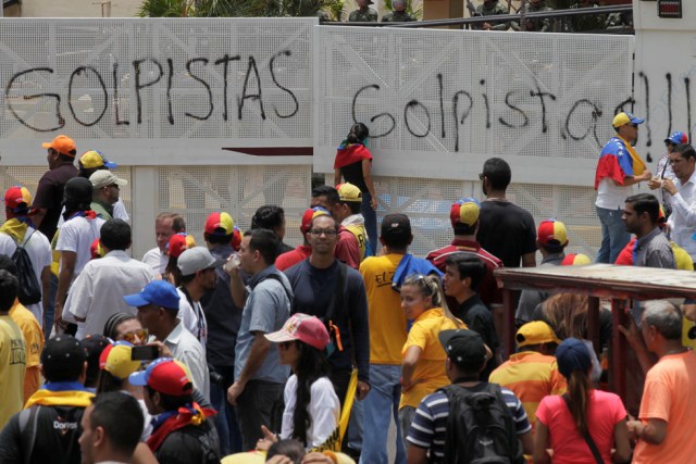 Opposition supporters gather near an anti-riot barricade with a graffiti that reads "coup" during a rally against Venezuela's President Nicolas Maduro's government in Maracaibo, Venezuela April 8, 2017. REUTERS/Isaac Urrutia FOR EDITORIAL USE ONLY. NO RESALES. NO ARCHIVES.
