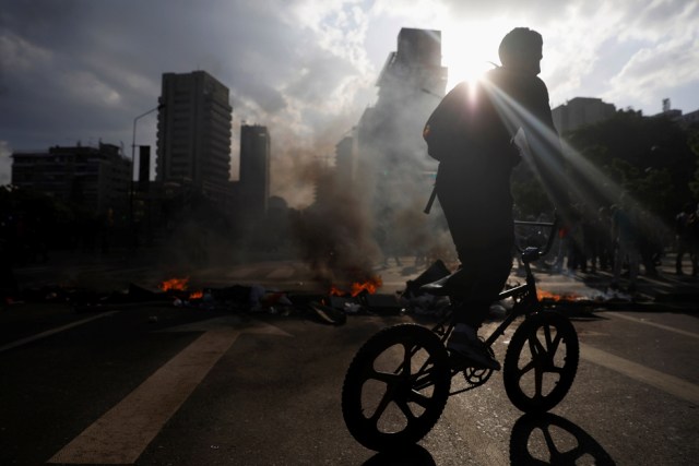 A demonstrator rides his bicycle near a fire barricade during a rally in Caracas, Venezuela, April 8, 2017. REUTERS/Carlos Garcia Rawlins