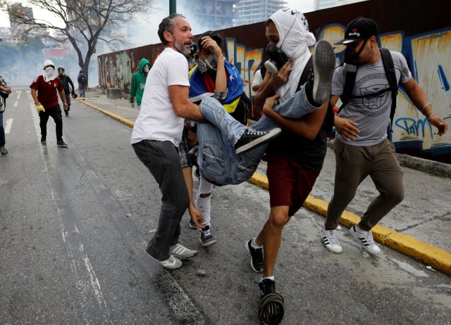 Uno de los afectados por gases lacrimógenos es atendido por compañeros durante una manifestación en abril 10, 2017. REUTERS/Carlos Garcia Rawlins