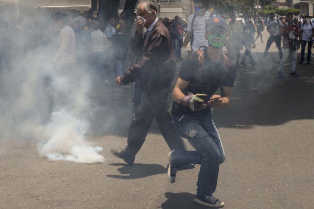 Demonstrators clash with the riot police during a protest against Venezuelan President Nicolas Maduro, in Caracas on April 20, 2017. Venezuelan riot police fired tear gas Thursday at groups of protesters seeking to oust President Nicolas Maduro, who have vowed new mass marches after a day of deadly unrest. Police in western Caracas broke up scores of opposition protesters trying to join a larger march, though there was no immediate repeat of Wednesday's violent clashes, which left three people dead. / AFP PHOTO / Federico PARRA