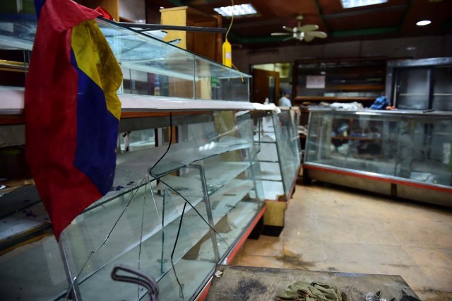 Picture taken on April 20, 2017 showing the damages casued by looters in a business in Caracas a day after demonstrations pro and against the government of Venezuelan President Nicolas Maduro. Venezuelan riot police fired tear gas Thursday at groups of protesters seeking to oust Maduro, who have vowed new mass marches after a day of deadly unrest. On the eve, hundreds of thousands of people fed up with food shortages and demanding elections joined protest marches in Caracas and several other cities while thousands of Maduro's supporters held a counter-rally in central Caracas.  / AFP PHOTO / Ronaldo SCHEMIDT