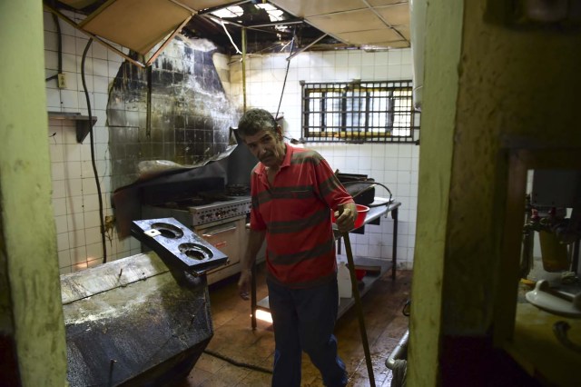 A man picks up the mess at a business in Caracas on April 20, 2017 a day after looting occurred after demonstrations pro and against the government of Venezuelan President Nicolas Maduro. Venezuelan riot police fired tear gas Thursday at groups of protesters seeking to oust Maduro, who have vowed new mass marches after a day of deadly unrest. On the eve, hundreds of thousands of people fed up with food shortages and demanding elections joined protest marches in Caracas and several other cities while thousands of Maduro's supporters held a counter-rally in central Caracas.  / AFP PHOTO / Ronaldo SCHEMIDT